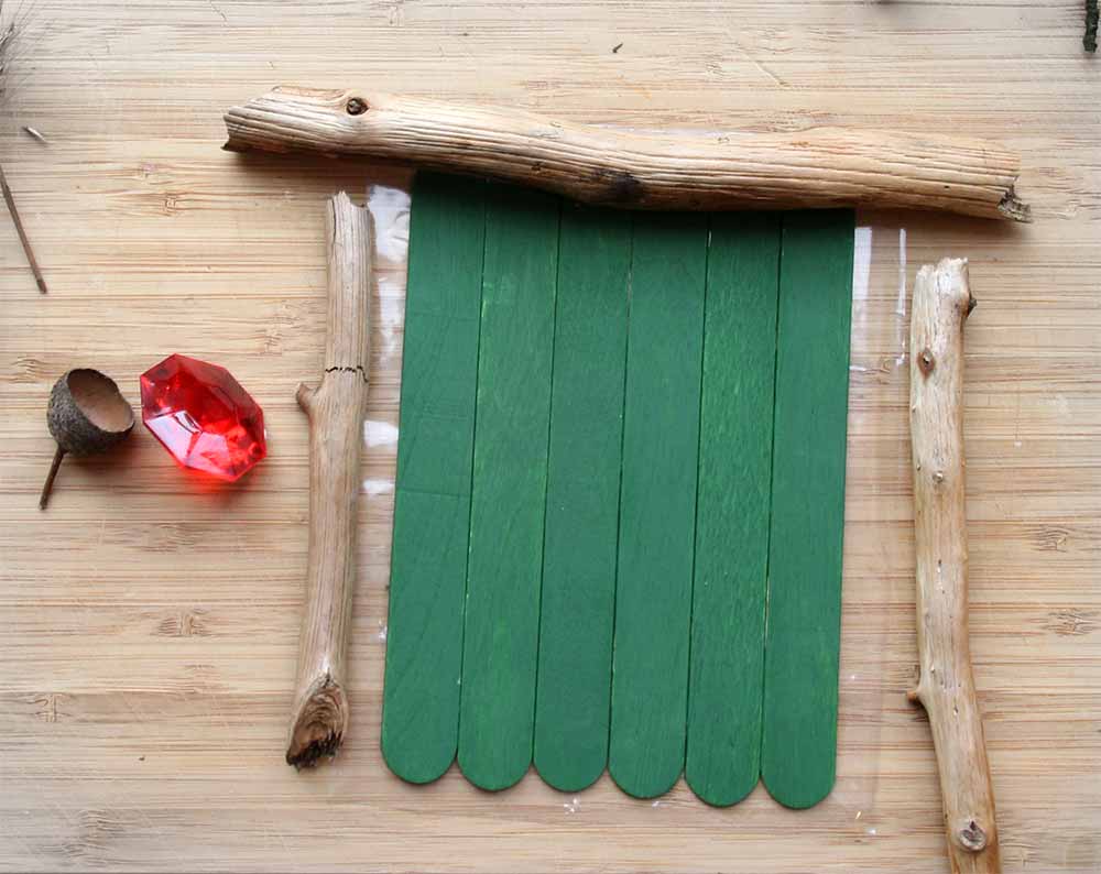 Der Wichteltür-Rohling Wichteltür in grün mit kleinen Ästchen als Türzarge basteln