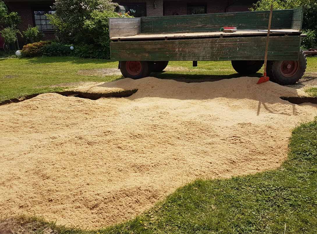 Fertiger Sandkasten: Der Aushub wird mit Bausand bis zur Rasenkante aufgefüllt.